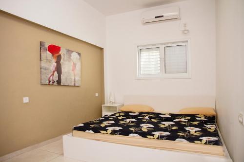 1 dormitorio con 1 cama y una pintura en la pared en Apartment Happiness, en Bat Yam