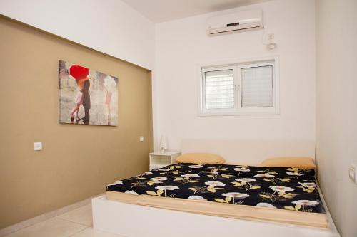 a bedroom with a bed and a painting on the wall at Apartment Happiness in Bat Yam