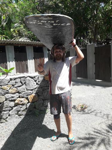 a man holding up a surfboard on his head at Hidden Well Hiriketiya in Hiriketiya