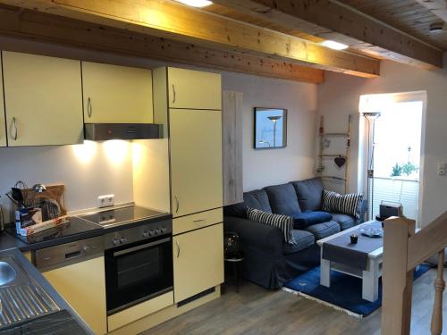 uma cozinha e sala de estar com armários amarelos e um sofá em Ein kleines Haus em Fehmarn