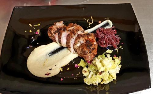 a black plate of food with meat and vegetables at Hotel Rodella in Selva di Val Gardena