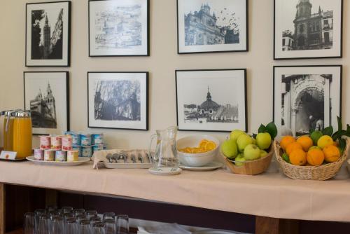 uma mesa com fruta sobre ela com imagens na parede em Hotel Alcántara em Sevilha