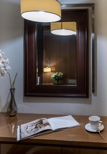 a book on a table with a mirror and a coffee cup at Cosmopolitan Hotel in Paralia Katerinis
