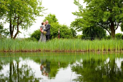 a bride and groom standing next to a body of water at Lindenhof Gästehaus & Hofcafe in Kranenburg