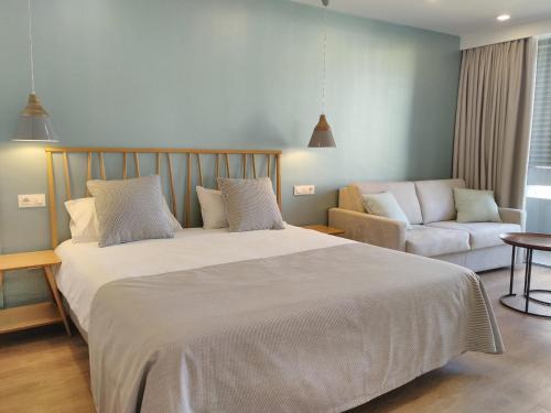 a bedroom with a large bed and a couch at Apartamentos Ciudad Jardín in Las Palmas de Gran Canaria