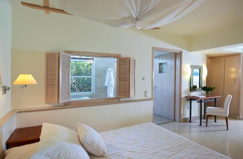 a bedroom with a bed and a window and a desk at St. Nicolas Bay Resort Hotel & Villas in Agios Nikolaos