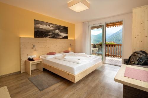 a bedroom with a large bed and a balcony at Mounthotel Niggl in Nova Levante
