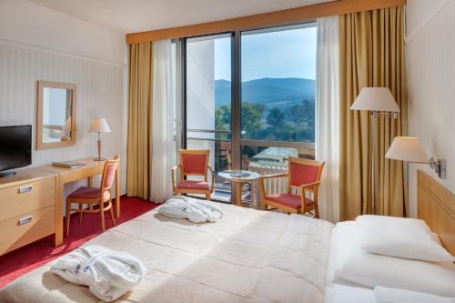 a hotel room with a bed and a desk and chairs at Ensana Esplanade in Piešťany