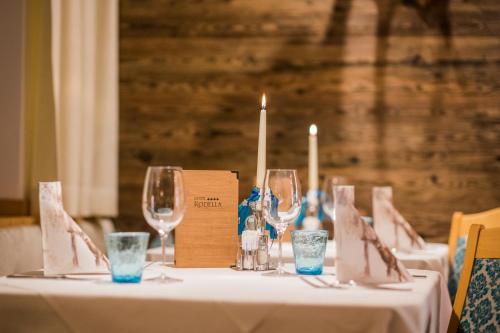 a table with wine glasses and candles on it at Hotel Rodella in Selva di Val Gardena