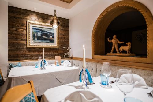 a dining room with two tables with white tablecloths at Hotel Rodella in Selva di Val Gardena