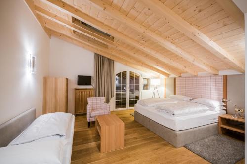 a large bedroom with two beds and a table at Hotel Rodella in Selva di Val Gardena