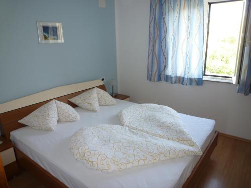 a bed with a white comforter and pillows in a bedroom at Villa Simfonija in Malinska
