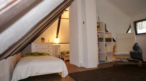a attic bedroom with a bed and a chair at Reethaus Niedlich in Middelhagen