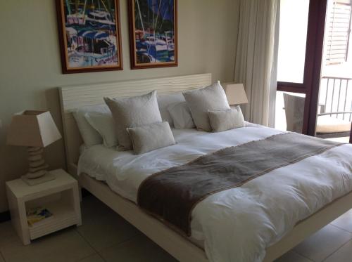 Eden Island luxury apartment sea view في جزيرة عدن: غرفة نوم بسرير كبير عليها شراشف ووسائد بيضاء