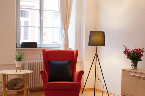a living room with a red chair and a lamp at Heidelberg Apheartments in Heidelberg