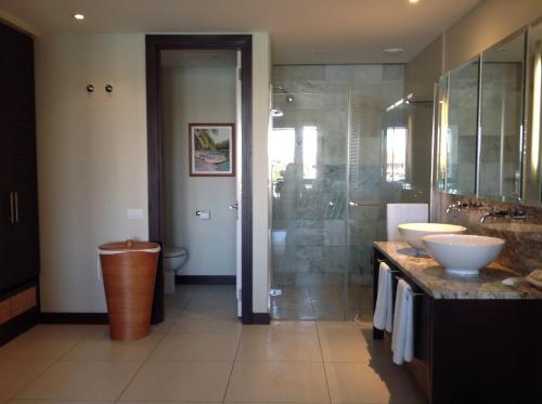 Eden Island luxury apartment sea view في جزيرة عدن: حمام مع مغسلتين ودش زجاجي