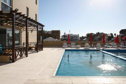 a swimming pool with chairs and umbrellas on a building at El Aguila del Tuyu in San Clemente del Tuyú
