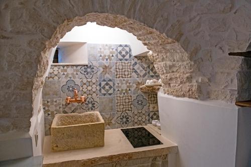 La salle de bains est pourvue d'un lavabo et d'un mur en pierre. dans l'établissement Suite DOMANGI Trullo Antonio, à Alberobello