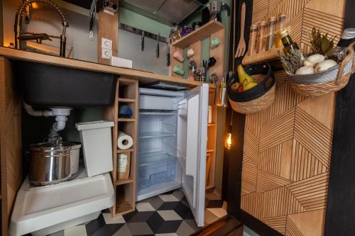 Elle comprend une petite cuisine équipée d'un réfrigérateur ouvert et d'un évier. dans l'établissement Studio - Les villas du triangle, à Nîmes