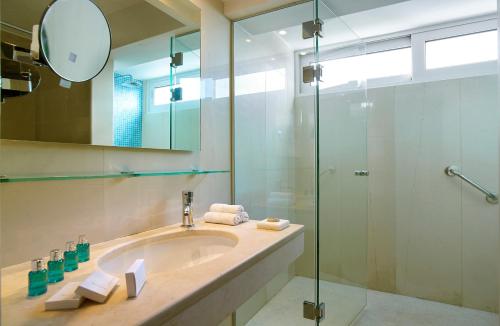a bathroom with a sink and a glass shower at St. Nicolas Bay Resort Hotel & Villas in Agios Nikolaos
