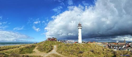 a lighthouse on top of a hill next to the ocean at Appartementen Dorp & Duin in Egmond aan Zee