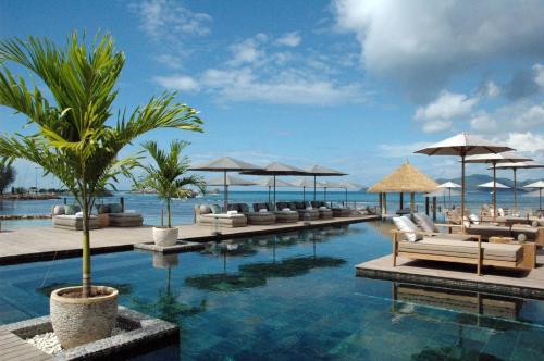 a resort with a pool with chairs and umbrellas at Le Domaine de L'Orangeraie Resort and Spa in La Digue