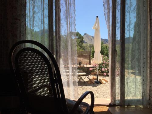 a chair sitting in front of a window with an umbrella at Can Elisa in Tárbena