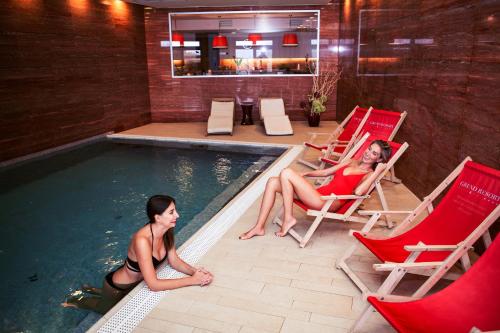 two women sitting in chairs in a swimming pool at Grund Resort Golf and Ski in Mladé Buky