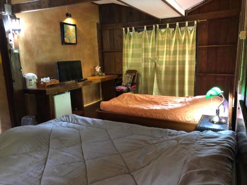 a bedroom with two beds and a desk with a computer at Ban Kaew Mo Ra Glamping & Restaurant in Pang Mapha