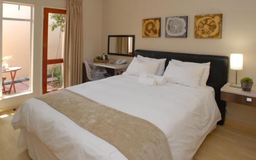 sypialnia z dużym białym łóżkiem i oknem w obiekcie The Lofts w mieście Polokwane