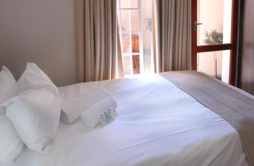 a white bed with white pillows and a window at The Lofts in Polokwane