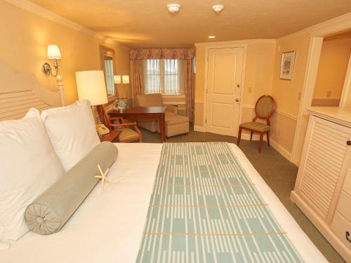 a room with a bed, chair, table and window at Anchor In Hotel - Hyannis, MA in Hyannis