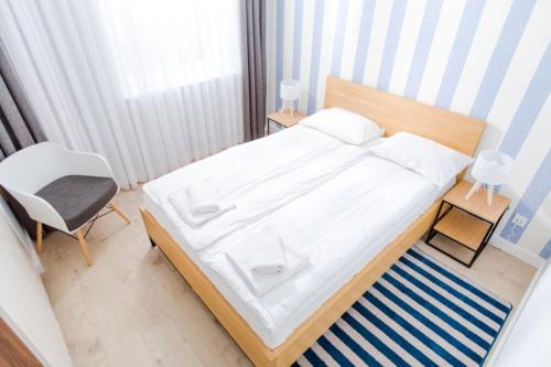 sypialnia z dużym białym łóżkiem i krzesłem w obiekcie Resort Apartamenty Klifowa Rewal 14 w Rewalu