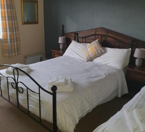 a bedroom with a large bed with white sheets and pillows at Queensberry Arms Hotel in Annan