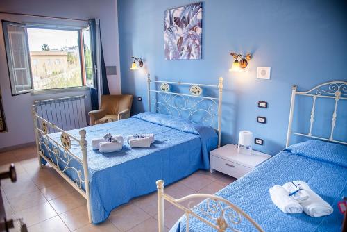 a blue bedroom with two beds and a window at SCIUSCIA' in Alcamo Marina