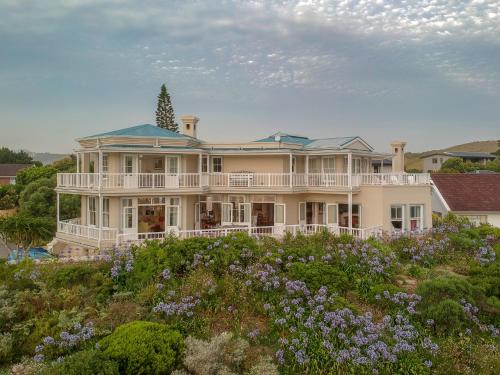 a large house on top of a hill with flowers at Isola Bella Guest House in Knysna
