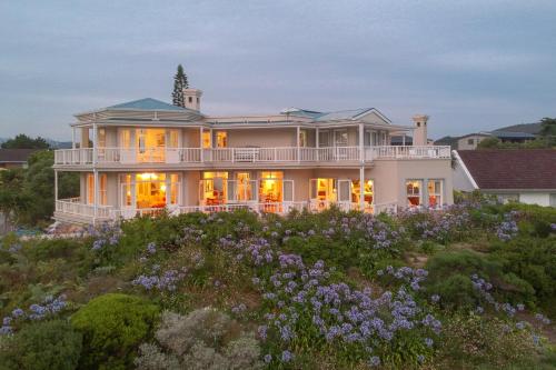 a large house on a hill with purple flowers at Isola Bella Guest House in Knysna