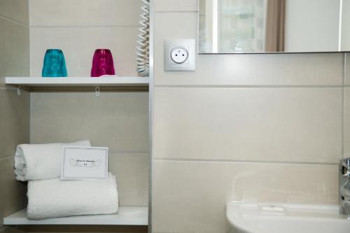 un baño con lavabo y un reloj en un estante en Hôtel Le Stanislas, en Nancy