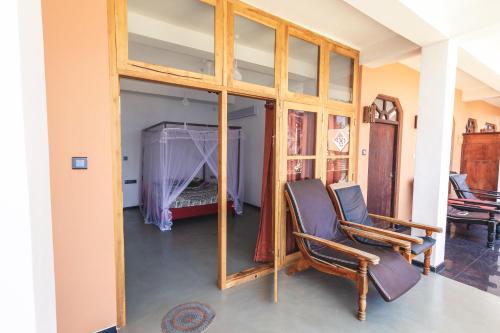 a room with a mirror and two chairs and a bed at Coppenrath Hostel in Tangalle