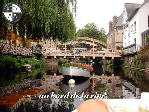 a boat in a river with a bridge in the background at Au Bord de la Rive B&B in Pontrieux