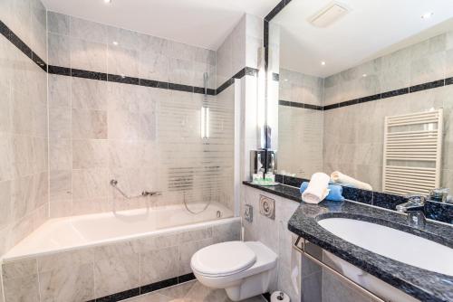 a bathroom with a tub and a toilet and a sink at Aparthotel Seeschlösschen in Zinnowitz