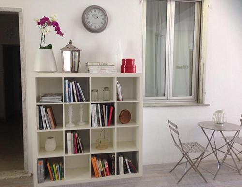 a book shelf with books and a clock on a wall at Hotel Spot Varazze in Varazze