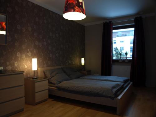 a bedroom with a bed and a window and a lamp at Apartament przy parku in Wrocław