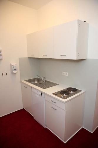 a kitchen with white cabinets and a sink at Twinhof in Hamburg