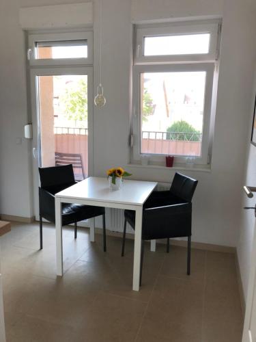 a white table and chairs in a room with two windows at Feel-Good Apartment In Mannheim-Neckarau in Mannheim