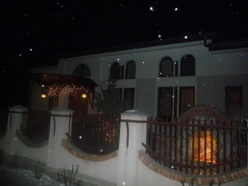 a building with a fence in front of it at night at Rapsodia Pension in Suceava