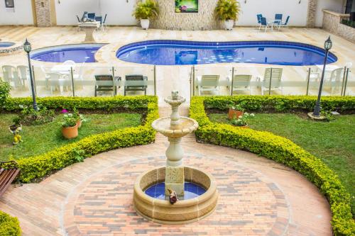 a fountain in a courtyard next to a swimming pool at Hotel Campestre Santa Catalina in San Gil