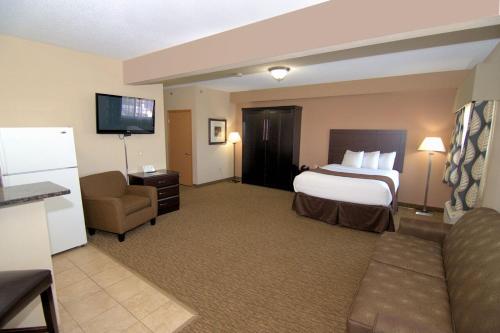 une chambre d'hôtel avec un lit, un canapé et une télévision dans l'établissement Rock Island Inn & Suites, à Atlantic