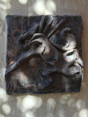 a bronze artifact with a face on a wall at Quinta Luna in Cholula