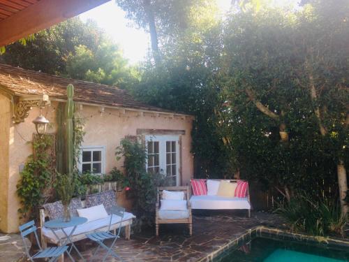 a patio with chairs and a pool in a backyard at Under the Tuscan Sun Cottage in West Los Angeles in Los Angeles